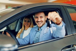 couple sitting in car holding up car keys